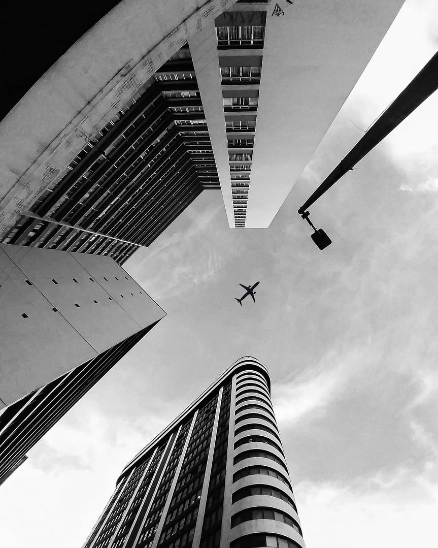 Low-Angle Photo of Airplane Flying over Building